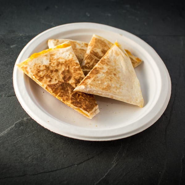 Golden-brown cheese quesadilla triangles on a white plate, ready to eat at Taco Pronto.